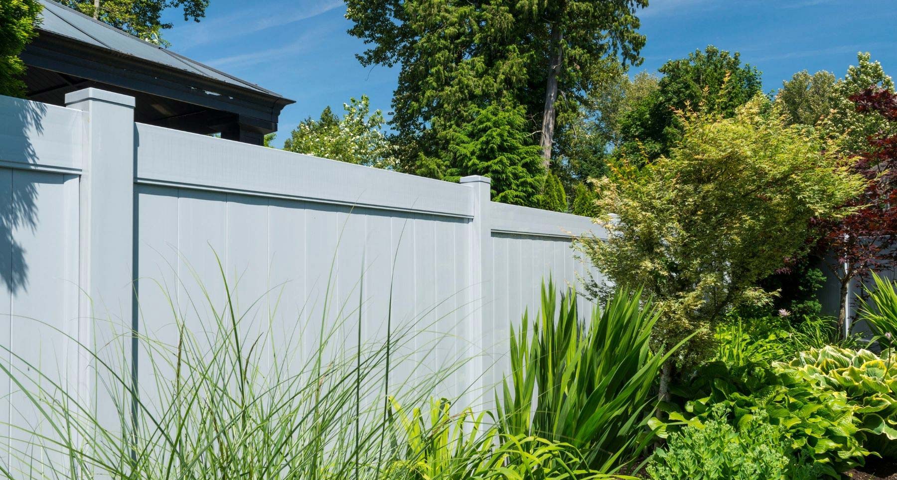 White vinyl privacy fence beside a planted garden bed in Vancouver BC