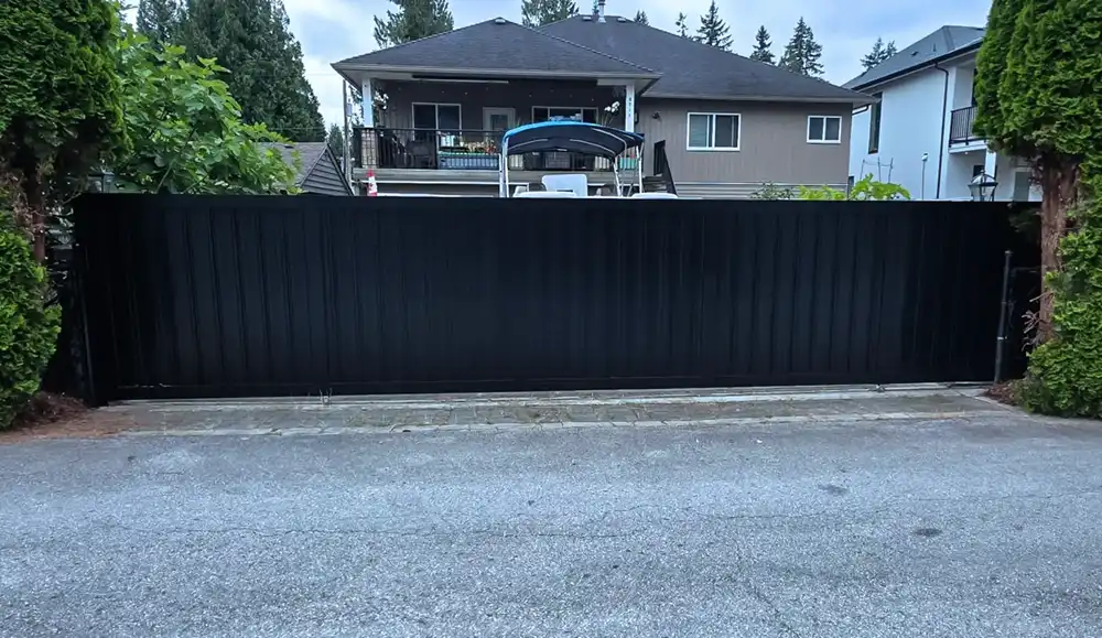Black privacy sliding gate installed across a residential driveway in Metro Vancouver
